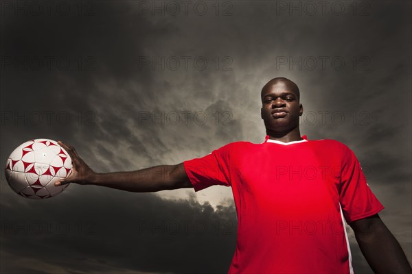 Black soccer player holding ball