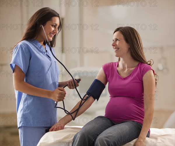 Nurse taking pregnant mother's blood pressure