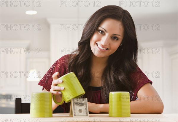 Mixed race woman finding money underneath cup