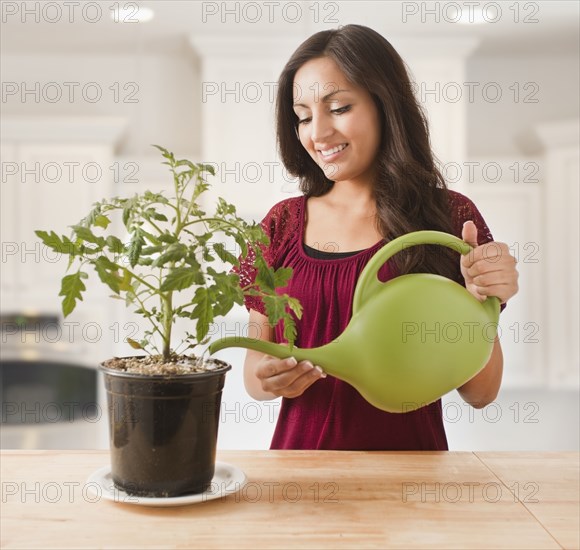 Mixed race woman watering plant