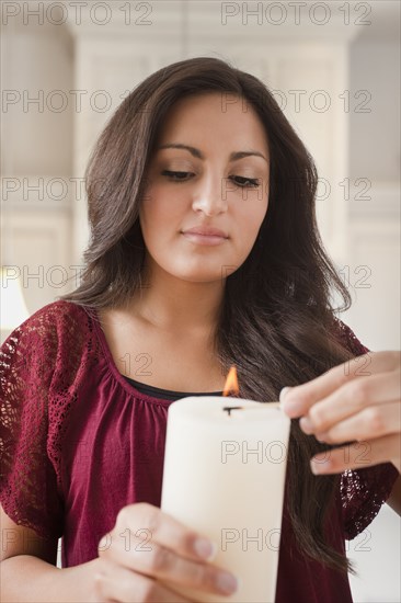 Mixed race woman lighting candle