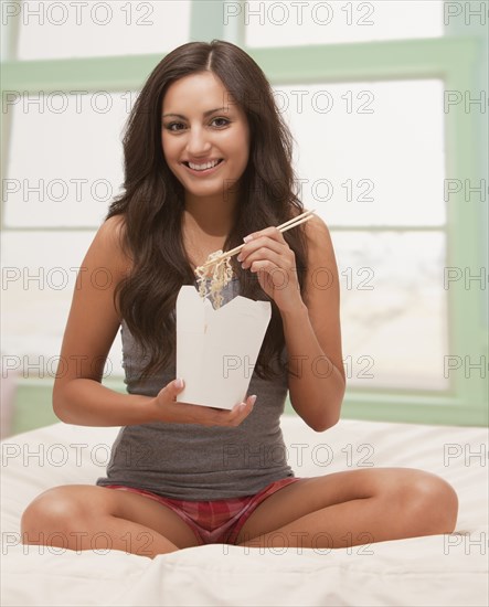 Mixed race woman eating Chinese food from carton