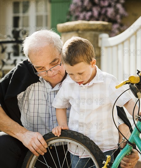 Caucasian grandfather and grandson repairing bicycle