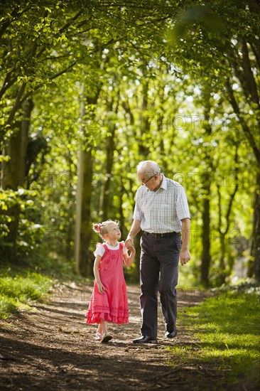 Caucasian grandfather and granddaughter walking in woods