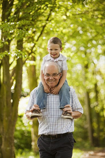 Caucasian grandfather carrying grandson on shoulders