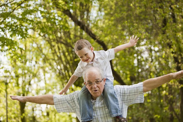 Caucasian grandfather carrying grandson on shoulders