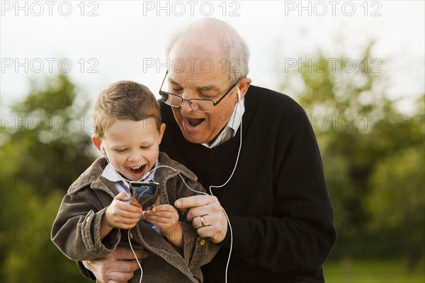 Caucasian grandfather and grandson listening to mp3 player