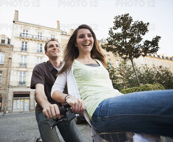 Caucasian couple riding bicycle together