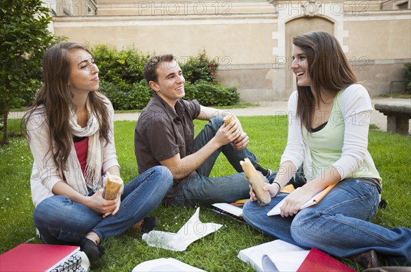 Caucasian friends eating lunch on grass