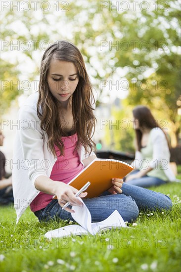 Caucasian woman studying in grass