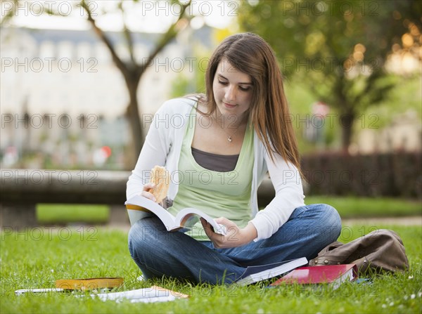 Caucasian student sitting in grass studying
