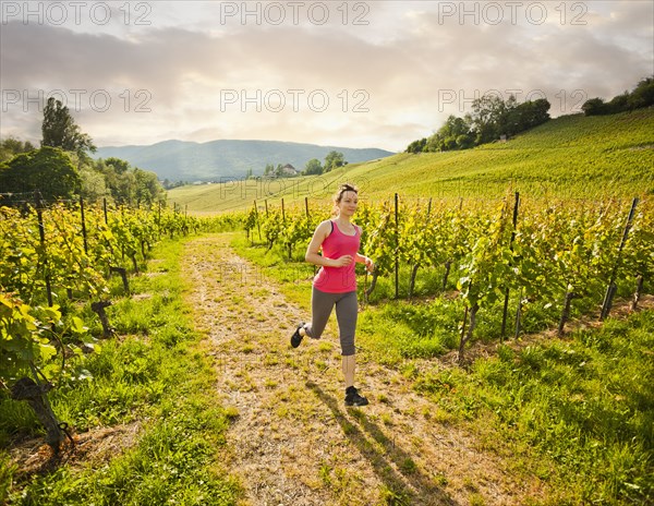 Caucasian woman running in vineyard