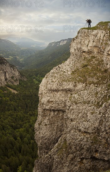 Caucasian man taking photographs from edge of cliff