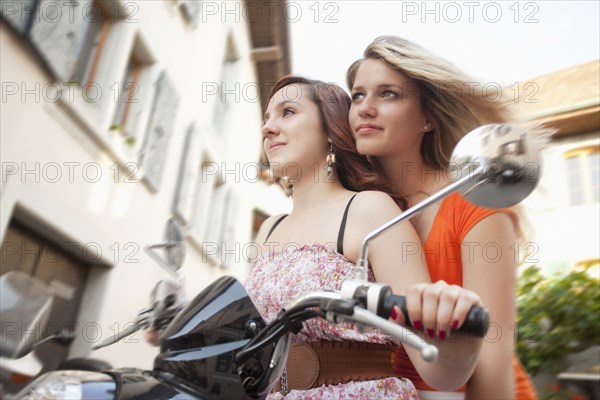 Caucasian friends riding scooter together