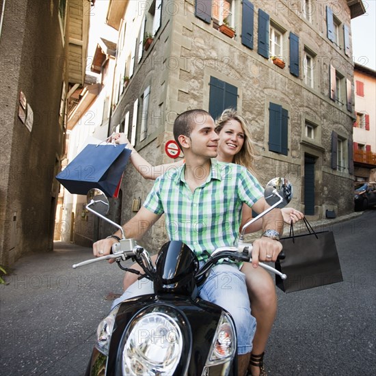 Couple riding scooter together