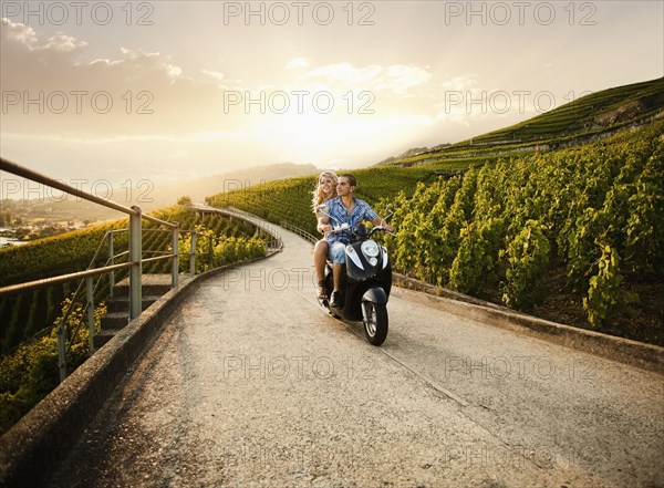 Couple riding scooter in vineyard