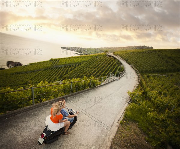 Couple riding scooter in vineyard