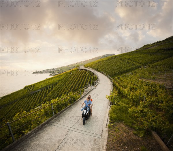 Couple riding scooter in vineyard