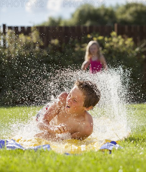 Caucasian boy sliding in water