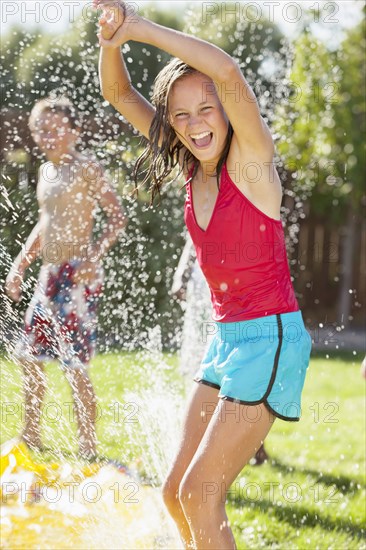 Caucasian girl playing in sprinkler