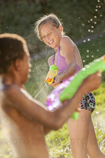 Children squirting each other with water guns