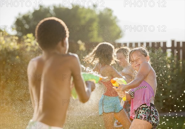 Children squirting each other with water guns