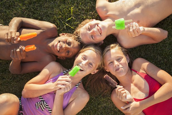 Children laying in grass eating popsicles