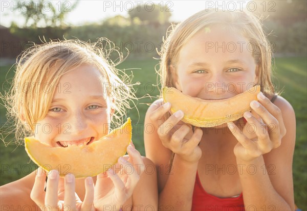Caucasian girls eating cantaloupe