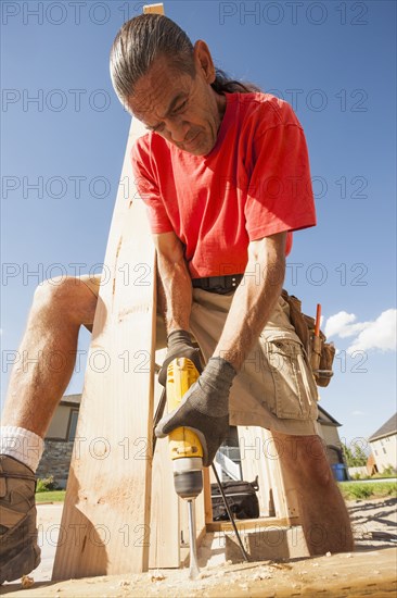 Hispanic man using drill on construction site