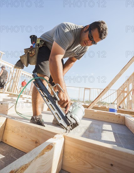 Caucasian man using nail gun on frame