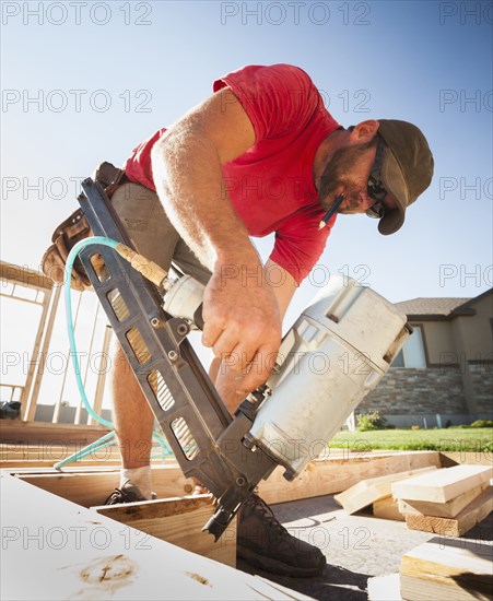 Caucasian man using nail gun on frame