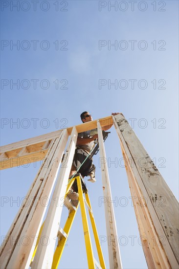 Caucasian man using nail gun on frame