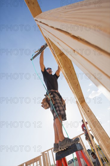 Caucasian man using nail gun on frame