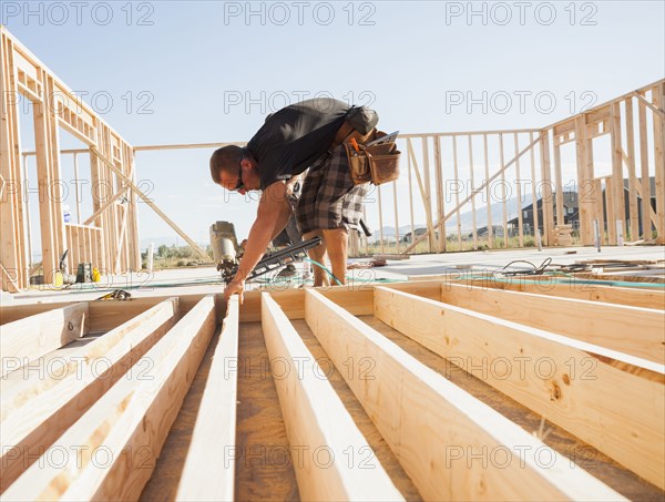 Caucasian man using nail gun on frame