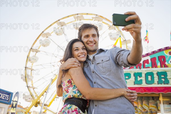 Caucasian couple taking self-portrait at carnival