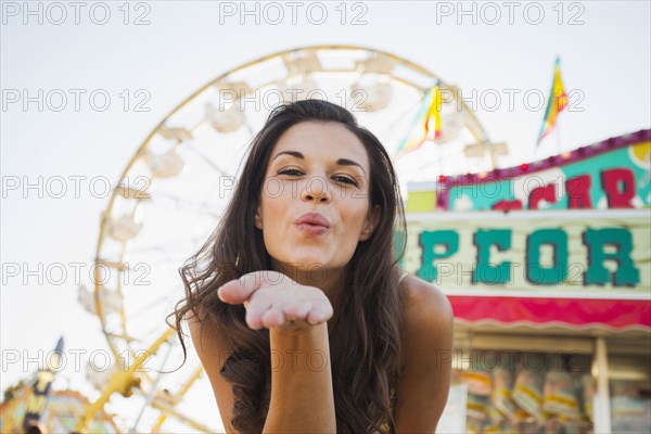 Caucasian woman at carnival blowing a kiss