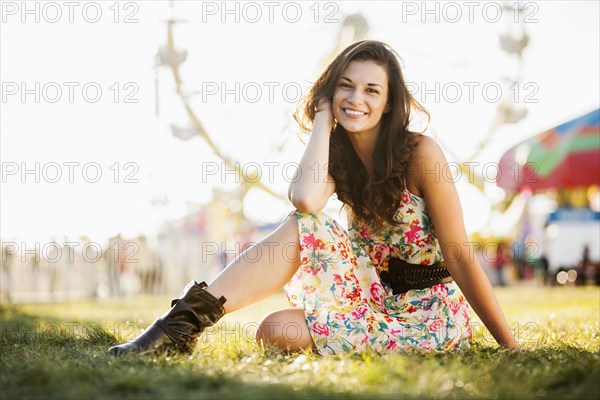 Caucasian woman sitting in grass at carnival