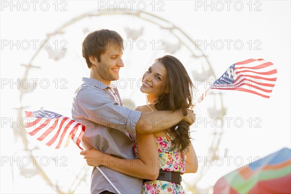 Caucasian couple holding American flags and enjoying carnival