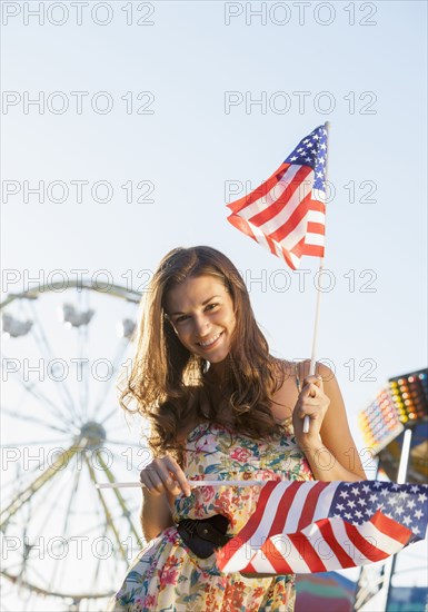Caucasian woman holding American flags at carnival