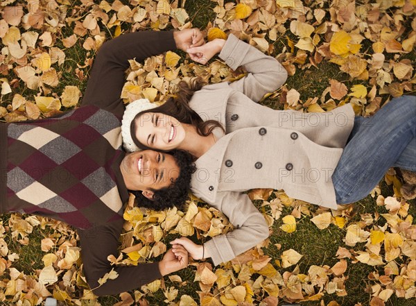 Couple laying in autumn leaves