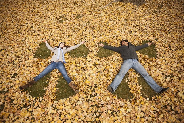 Couple making angel in autumn leaves