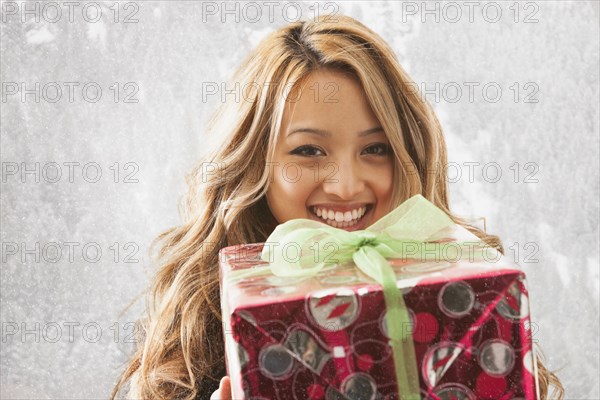 Mixed race woman holding present in snow