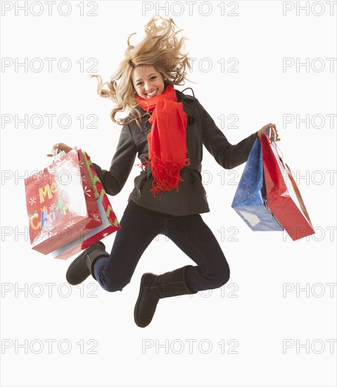 Mixed race woman jumping with shopping bags