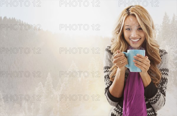 Mixed race woman drinking coffee in snow
