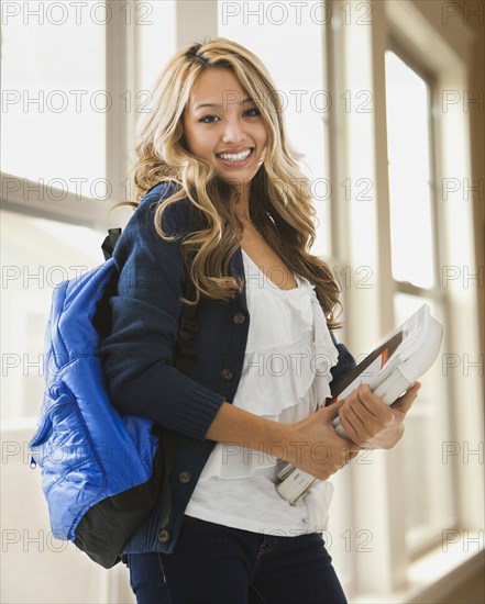 Mixed race student carrying books on campus