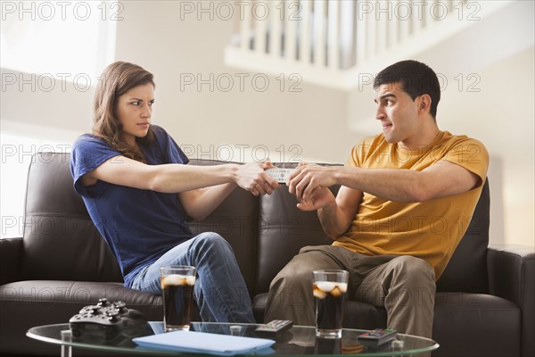 Couple arguing over remote on sofa