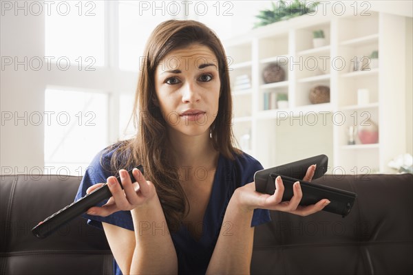 Caucasian woman with multiple remotes on sofa