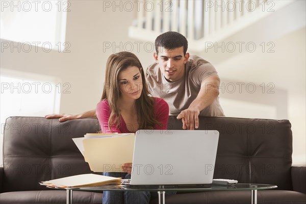 Couple reading papers at laptop together