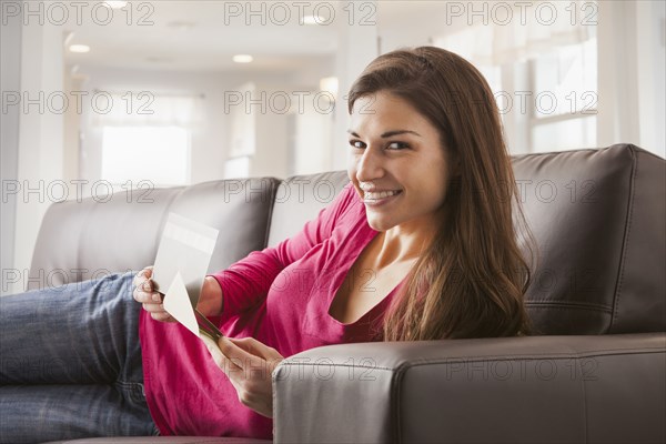 Caucasian woman reading papers on sofa