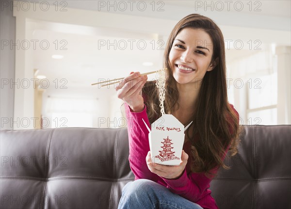 Caucasian woman eating Chinese food on sofa